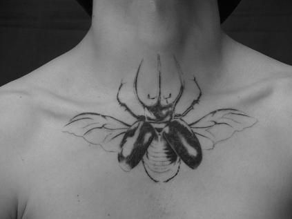 a black and white photo of a man's chest with a bee tattoo on it