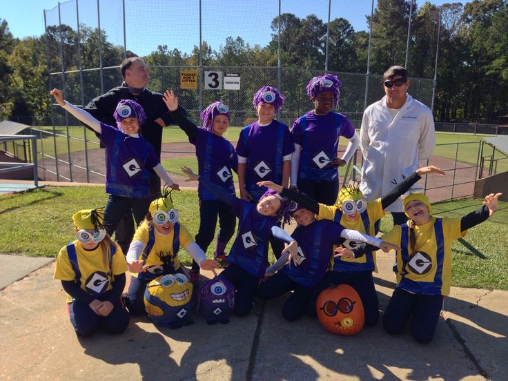 a group of young people standing next to each other in front of a baseball field