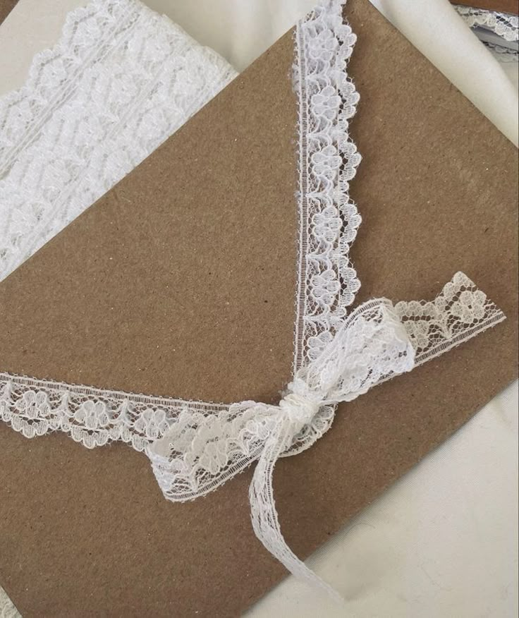 a brown card with white lace on it and a ribbon tied to the front of it