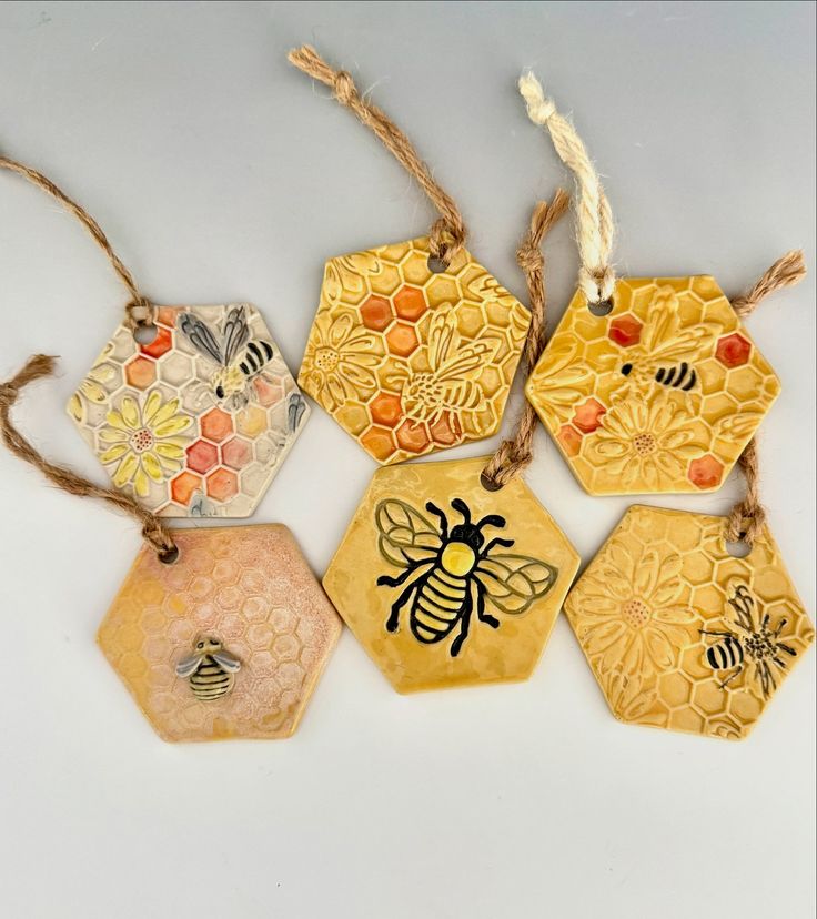 five bees and honeycombs are hanging from twine strings on a white surface