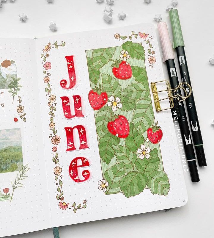 an open notebook with the word june written in red and green on it, surrounded by other items