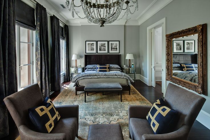 a bedroom with gray furniture and chandelier hanging from the ceiling in front of two windows