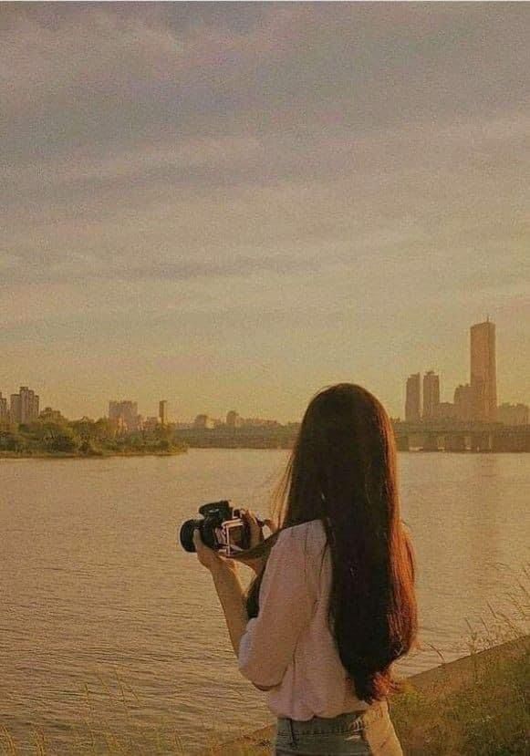 a woman holding a camera looking at the water