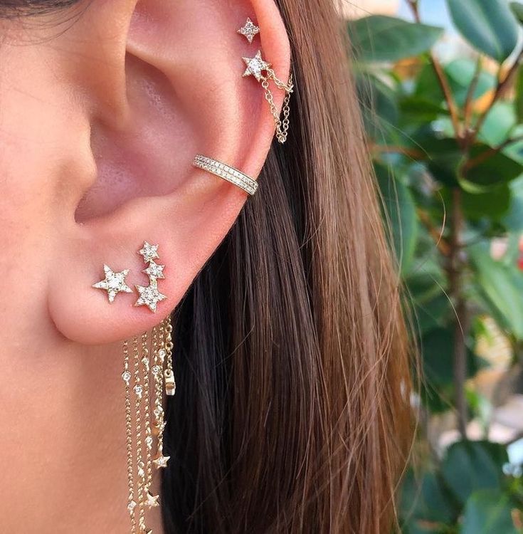 a close up of a person's ear with stars and chains attached to it