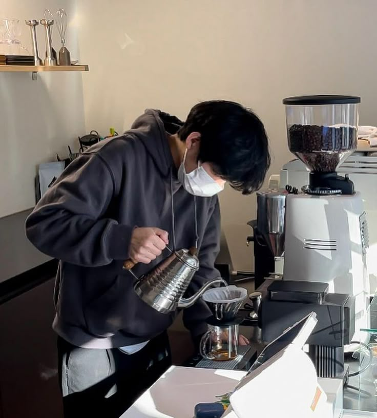 a man wearing a face mask while pouring coffee