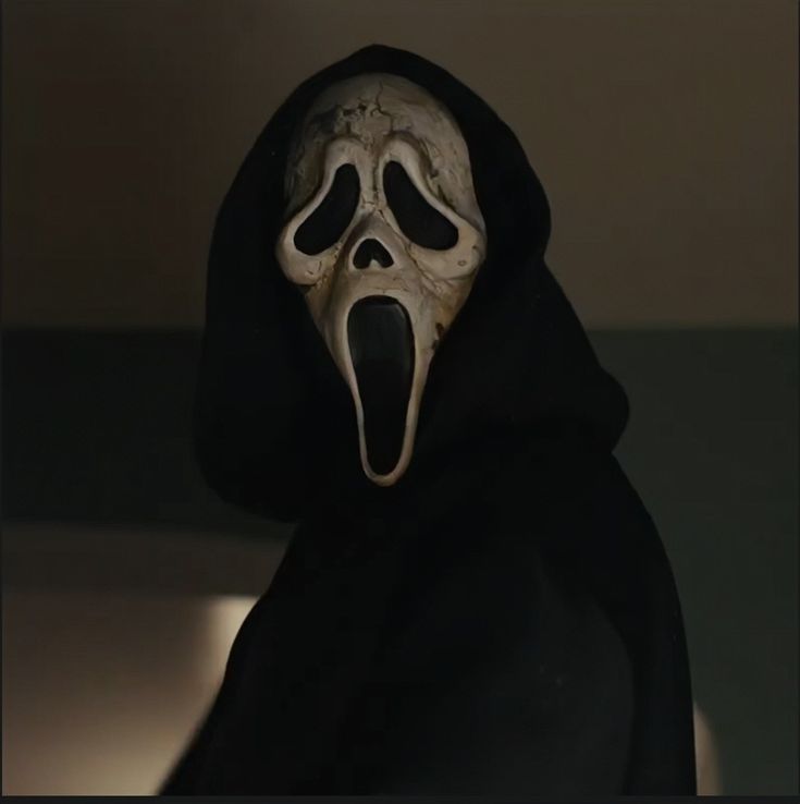 a person in a black hoodie with a white mask on and mouth wide open