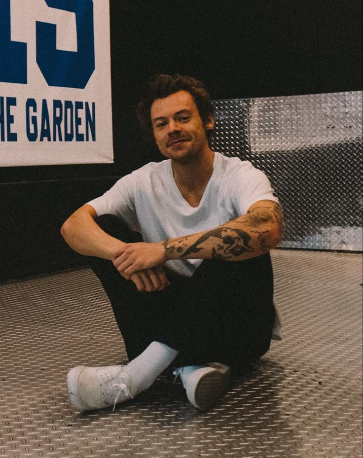 a man sitting on the ground in front of a sign