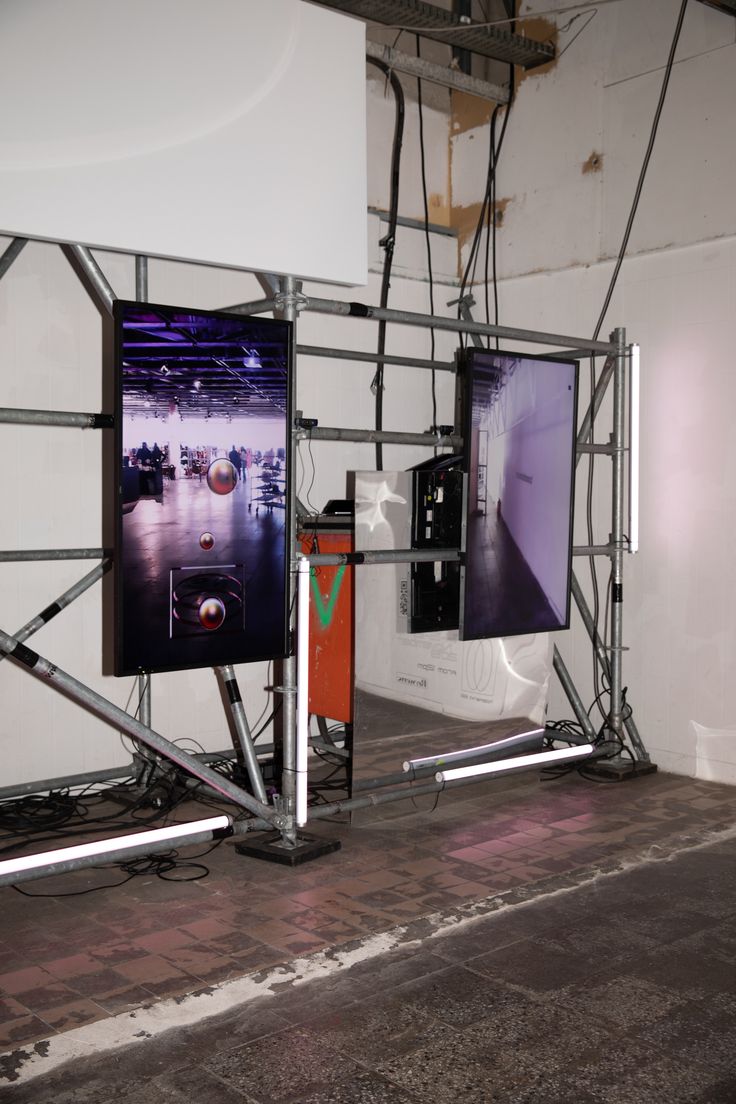 two televisions sitting on top of each other in front of a wall with wires attached to it