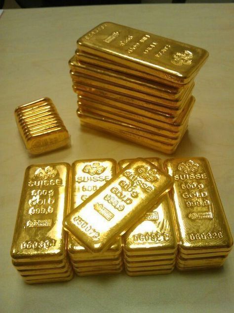 several stacks of gold bars sitting on top of a table next to some smaller ones