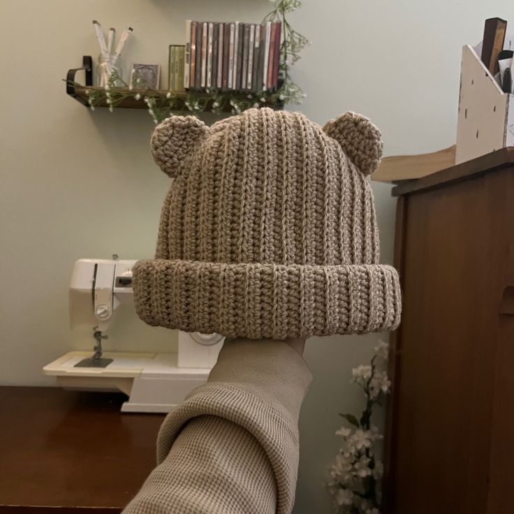 a knitted bear hat sitting on top of a sewing machine