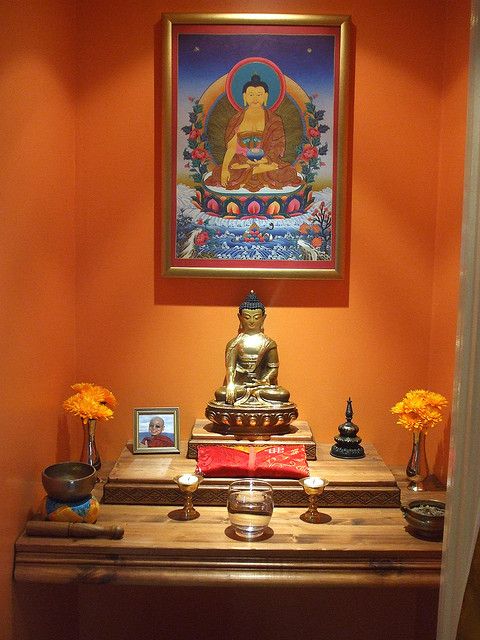 a buddha statue sitting on top of a wooden table in front of a framed painting