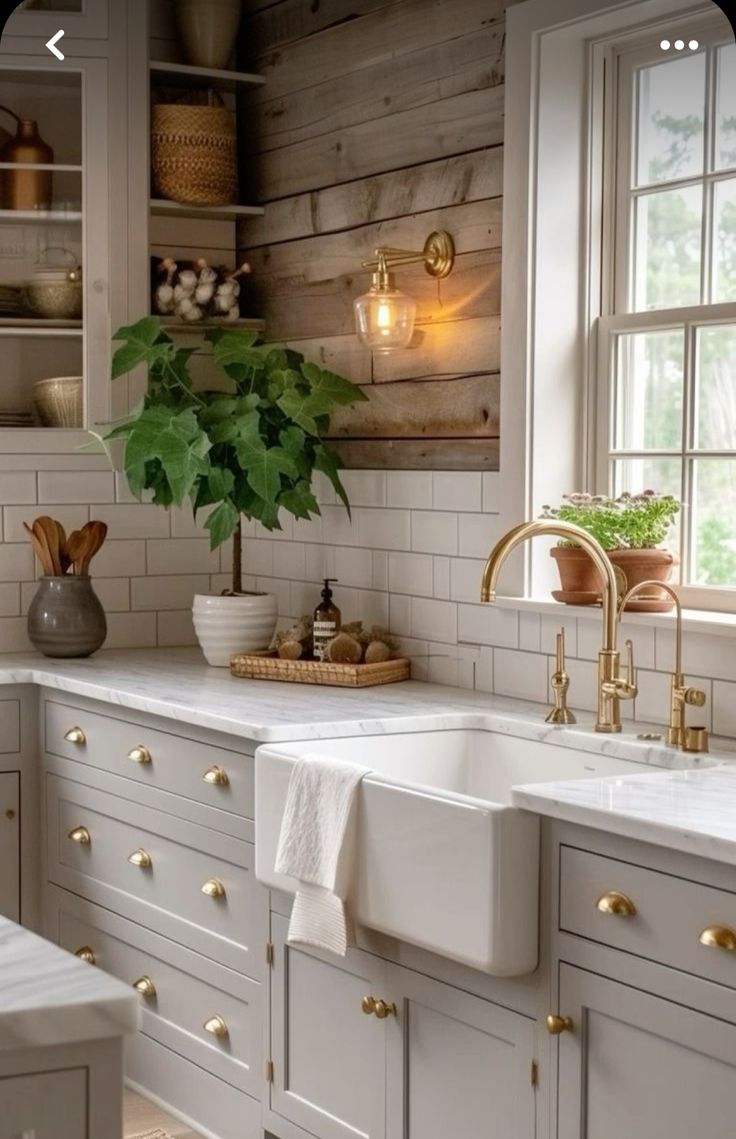 a kitchen with white cabinets and gold handles