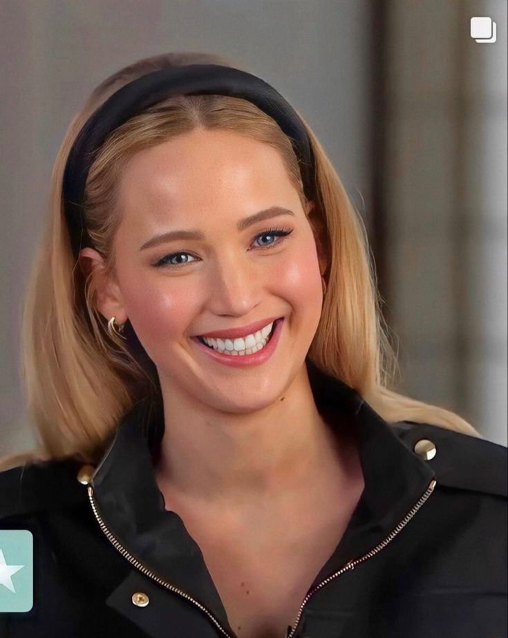 a close up of a person wearing a black shirt and headband smiling at the camera