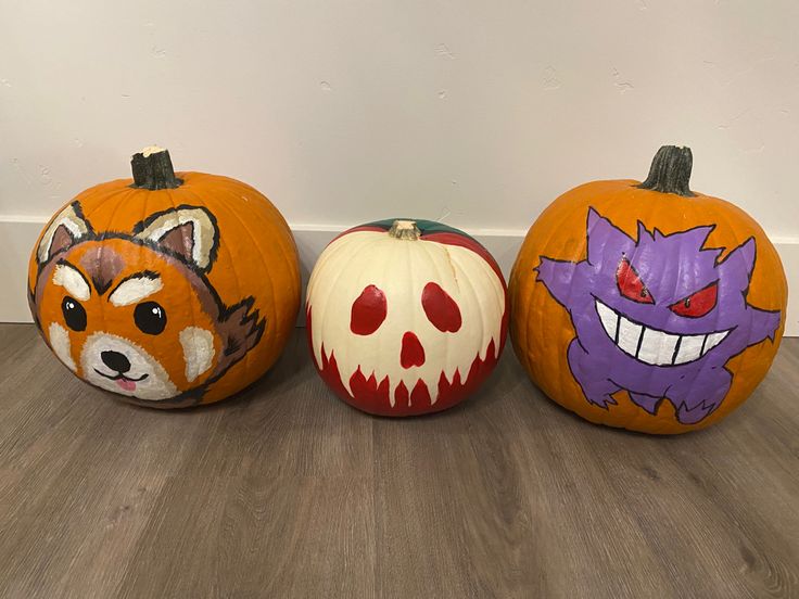 three painted pumpkins with different designs on them