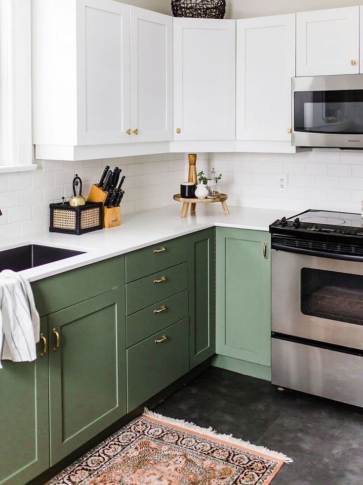 a kitchen with green cabinets and white counter tops, an area rug on the floor