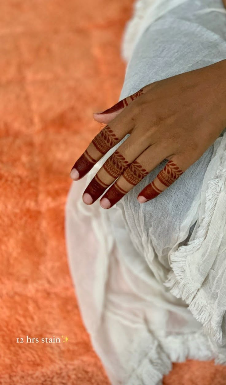 a woman's hand with henna tattoos on her left arm and the bottom half of her hands