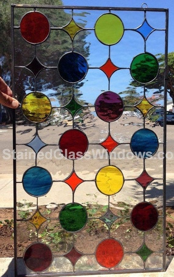 a multicolored glass window sitting on top of a sidewalk next to a tree