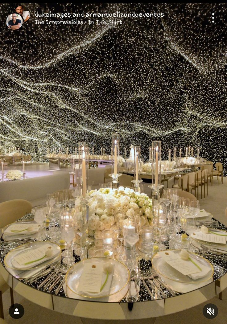 the table is set with white flowers and place settings for guests to sit down at