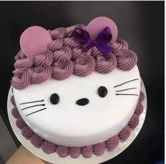 a cake decorated to look like a cat with pink icing and purple curls on top