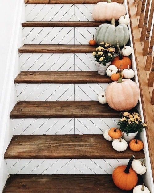 some pumpkins and gourds are sitting on the stair rail in this house