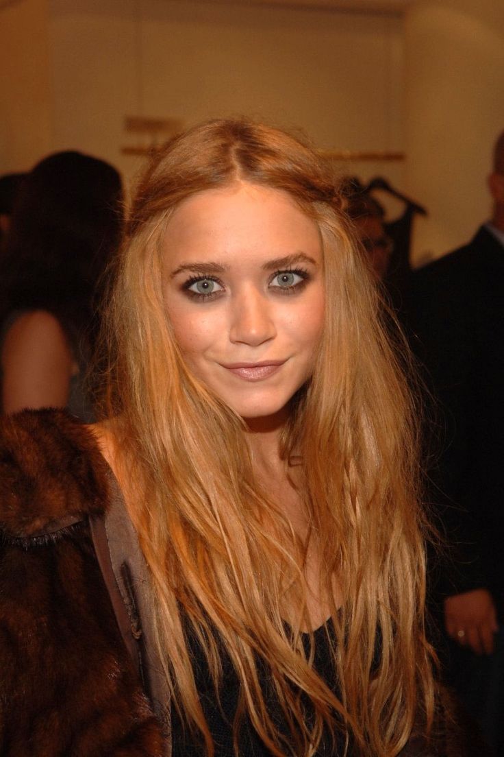 a woman with long blonde hair and blue eyes posing for the camera at an event