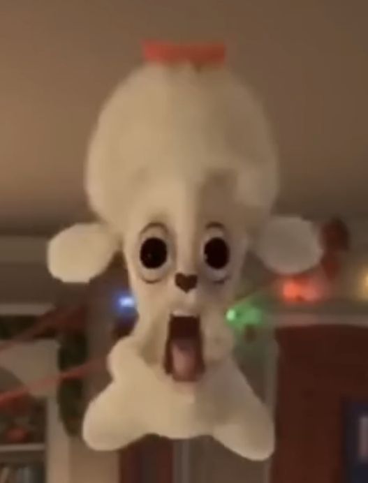 a stuffed animal hanging from the ceiling with its tongue out and eyes wide open,