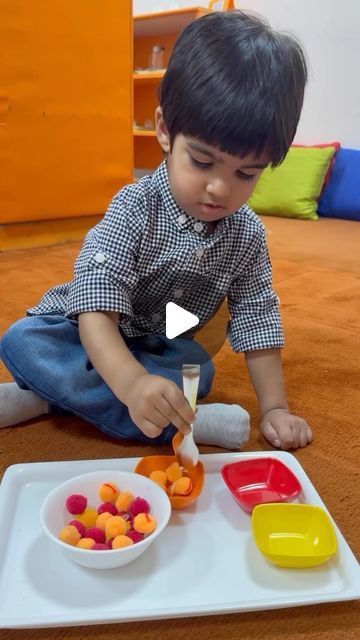 a little boy sitting on the floor playing with some food in front of his bowl