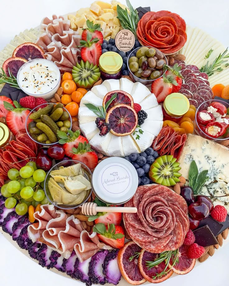 a platter filled with assorted meats, cheeses, and fruit is shown