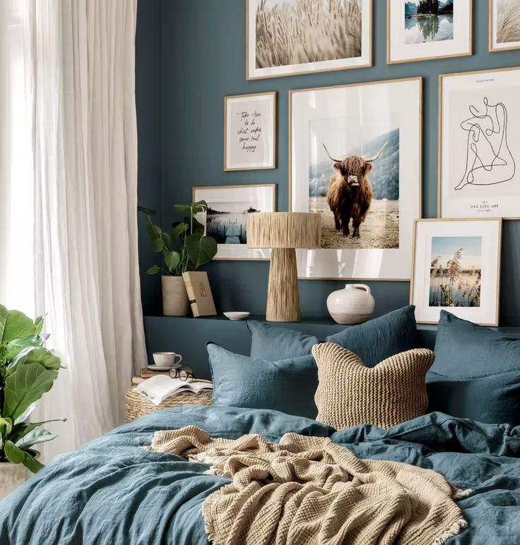 a bedroom with blue walls and pictures on the wall above the bed, along with pillows