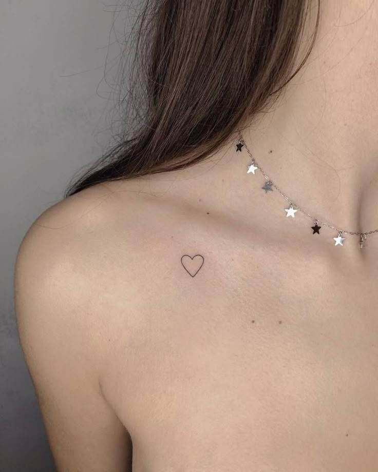 the back of a woman's shoulder with stars and heart tattoo on her chest