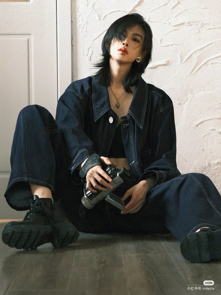 a woman sitting on the floor with a camera in her hand and wearing black shoes