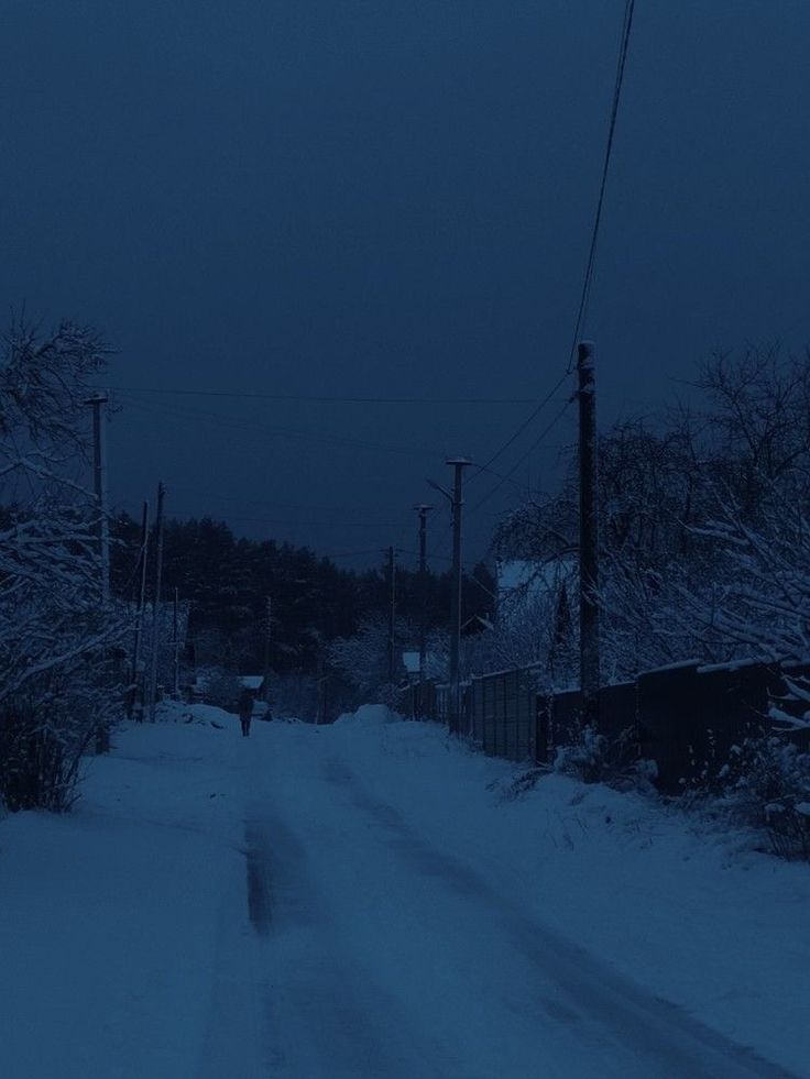 a person walking down a snowy road at night