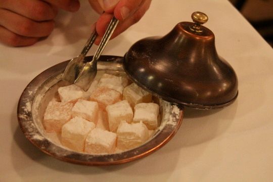 a person is spooning sugar cubes into a bowl with a salt shaker