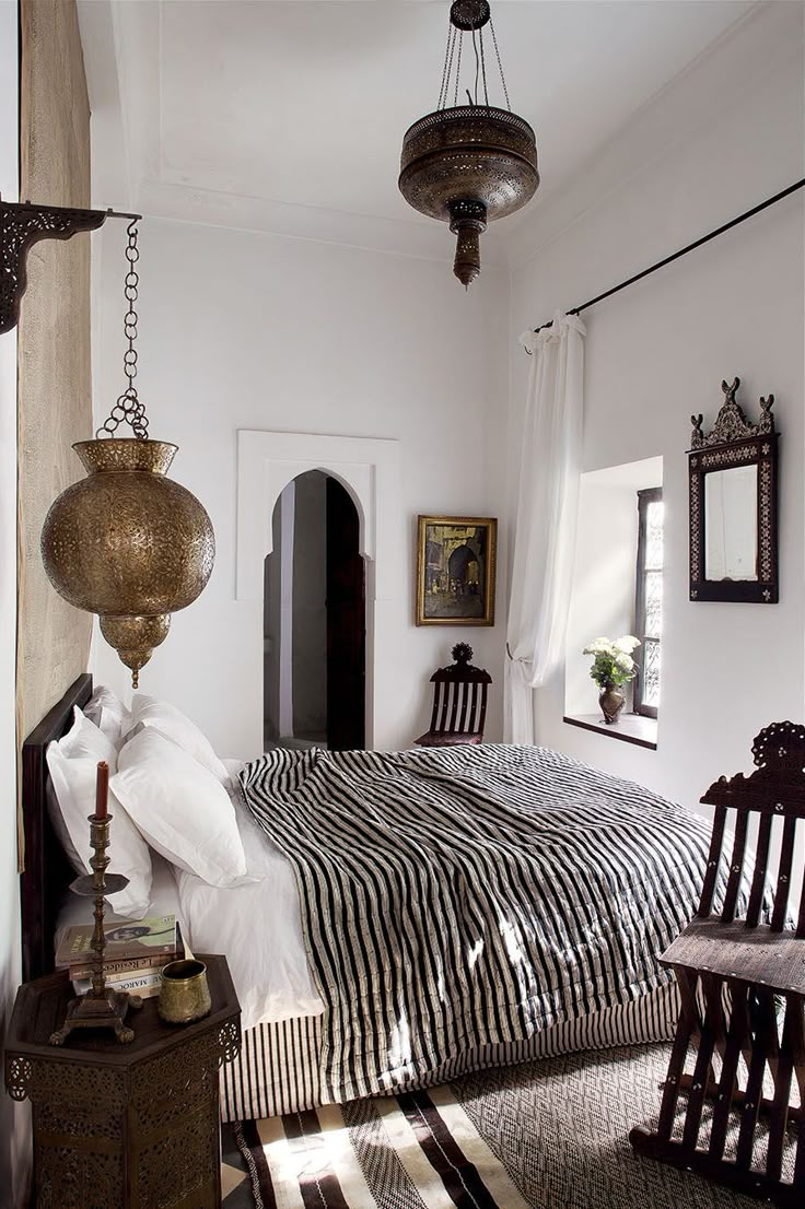 a bed room with a neatly made bed and two wooden chairs next to each other