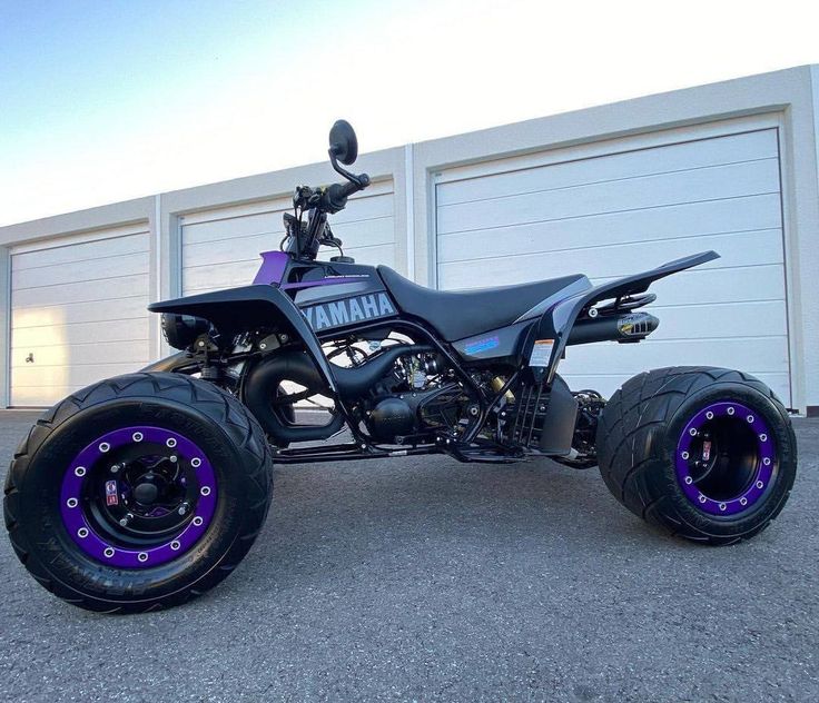 a purple and black four wheeler parked in front of a garage