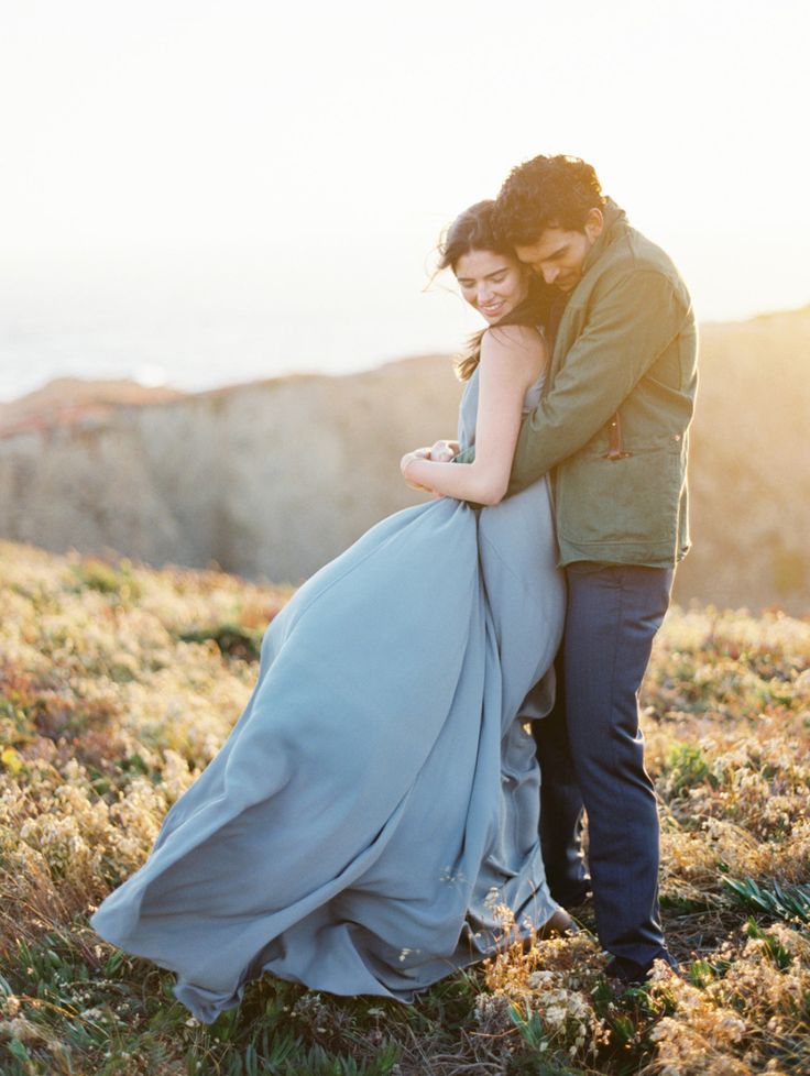 a man and woman standing next to each other on top of a grass covered field