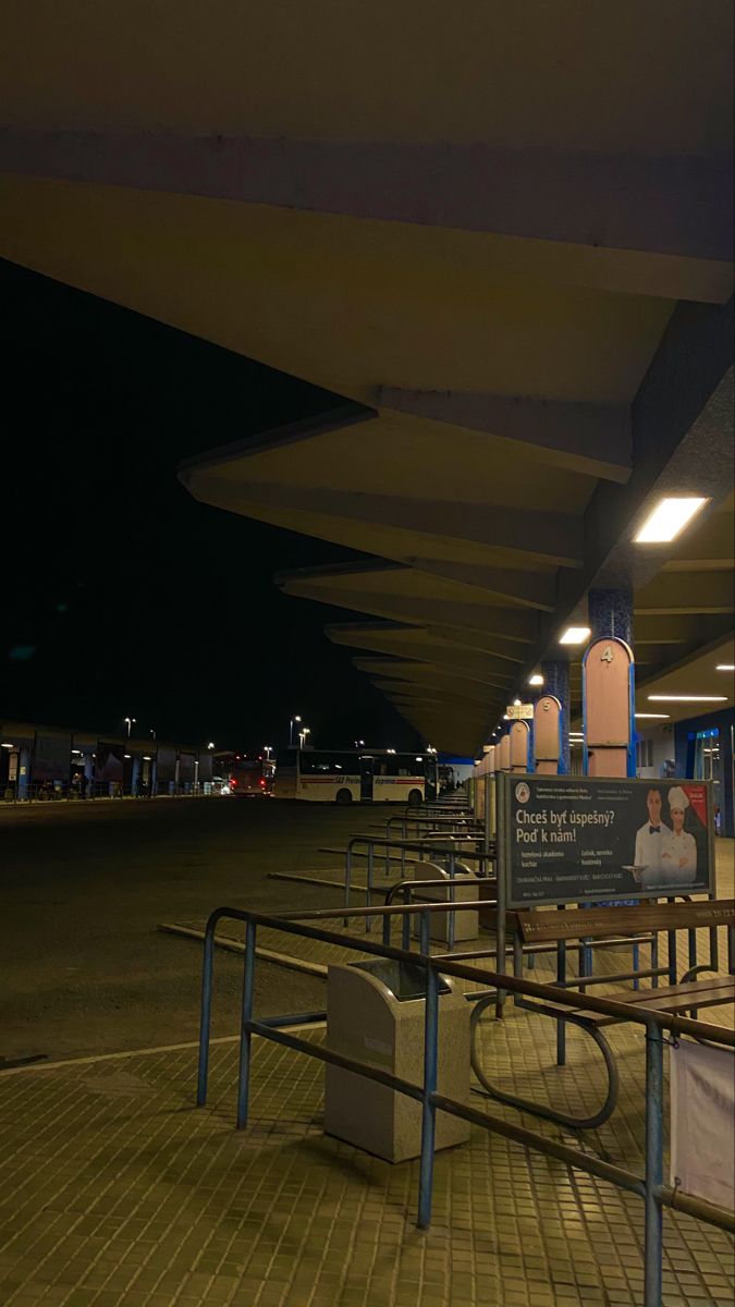 an empty parking lot at night with benches and signs