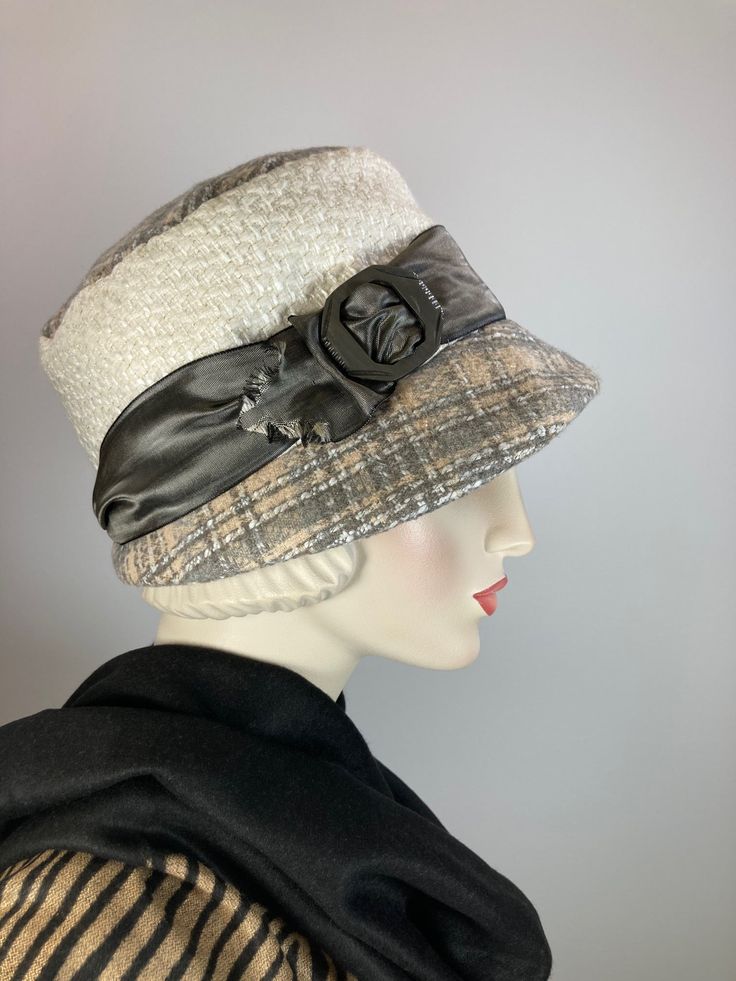 "Callie" is a soft plaid wool and boucle fabric hat. She is perfect for chilly weather and will keep you cozy warm (and stylish!) this winter. The top and brim of the hat is a pretty plaid in gray, white and beige. The side crown is an ivory boucle fabric with a bit of gold mylar sparkle that started life as an unworn skirt. It's topped with a water marked gray metallic ribbon laced through a vintage carved plastic buckle. It has an asymmetrical 1920s small brim and is easily packed for travel. Adjustable Brimmed Wool Cloche Hat, Cream Fedora Hat For Winter, Adjustable Wool Brimmed Cloche Hat, Cream Fedora Winter Hat, Beige Cloche Hat With Curved Brim For Fall, Adjustable Tweed Hat For Winter, Adjustable Beige Cloche Hat For Fall, Cream Fall Hat One Size Fits Most, White Bucket Hat For Fall