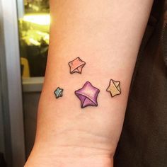 a person with a small tattoo on their arm that has different colored stars and envelopes