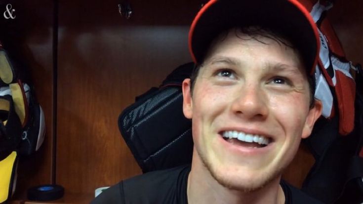 a young man wearing a baseball cap and smiling at the camera in his locker room