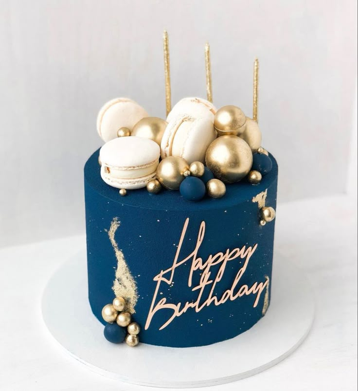 a birthday cake with gold and white decorations on it's blue frosted surface