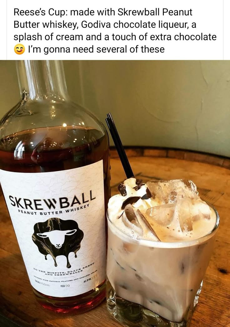 a bottle of skrewball and a glass filled with ice sits on a wooden table