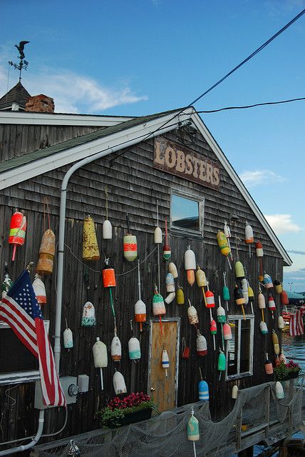 an old fishing shack is decorated with buoys and american flags