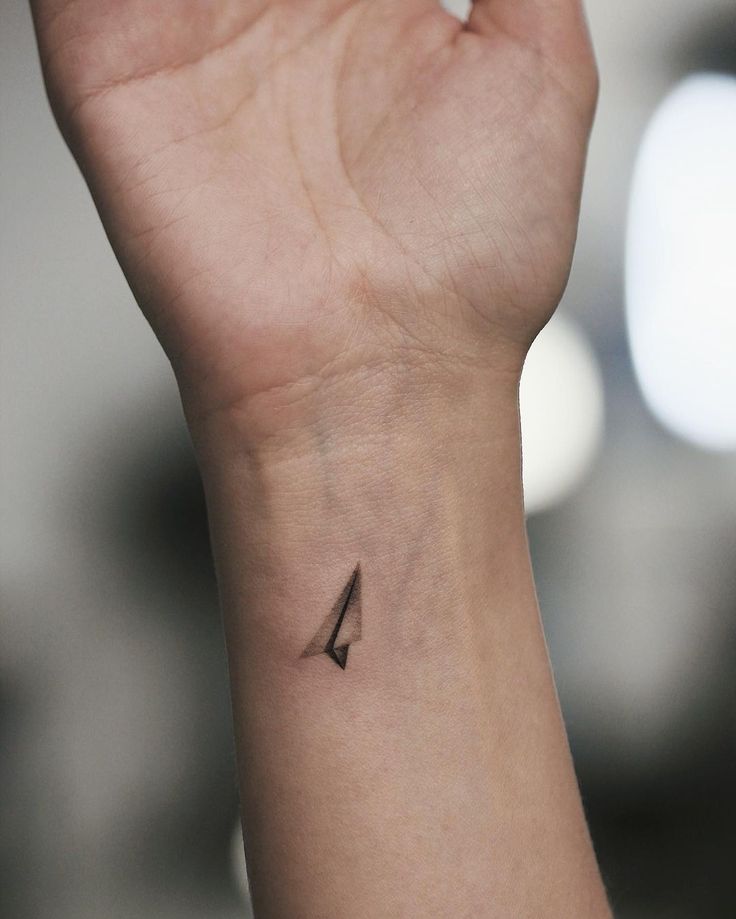 a person's wrist with a small arrow tattoo on the left side of their arm