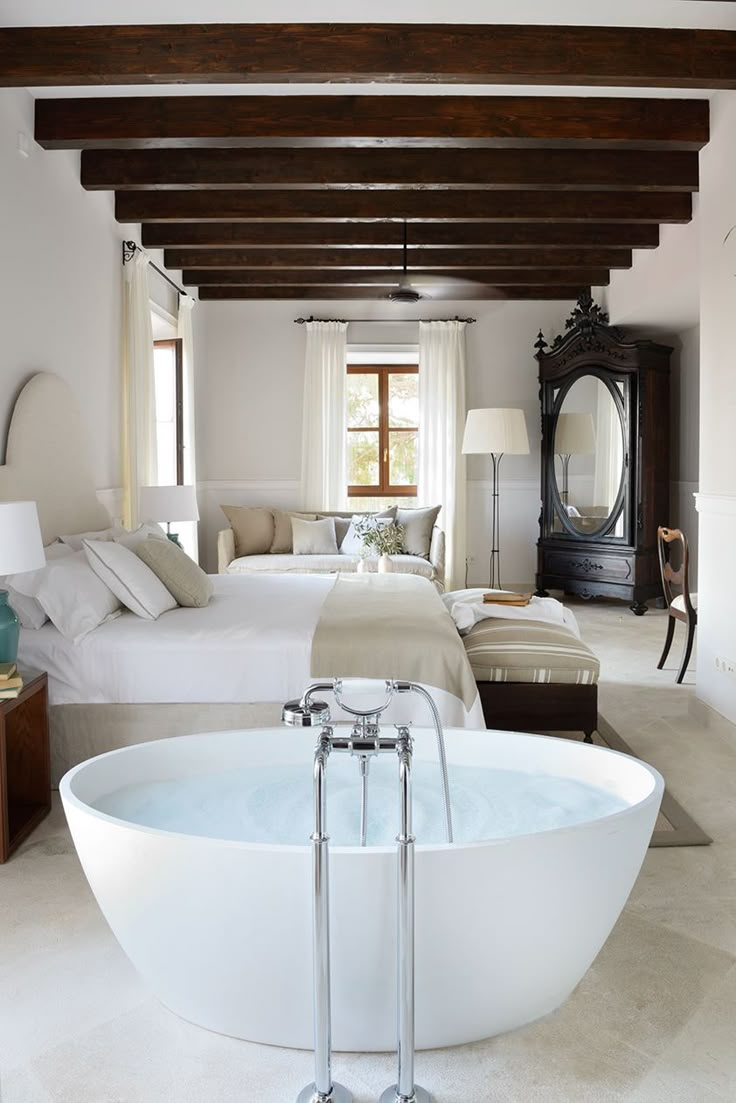 a large white bath tub sitting in the middle of a bedroom next to a bed