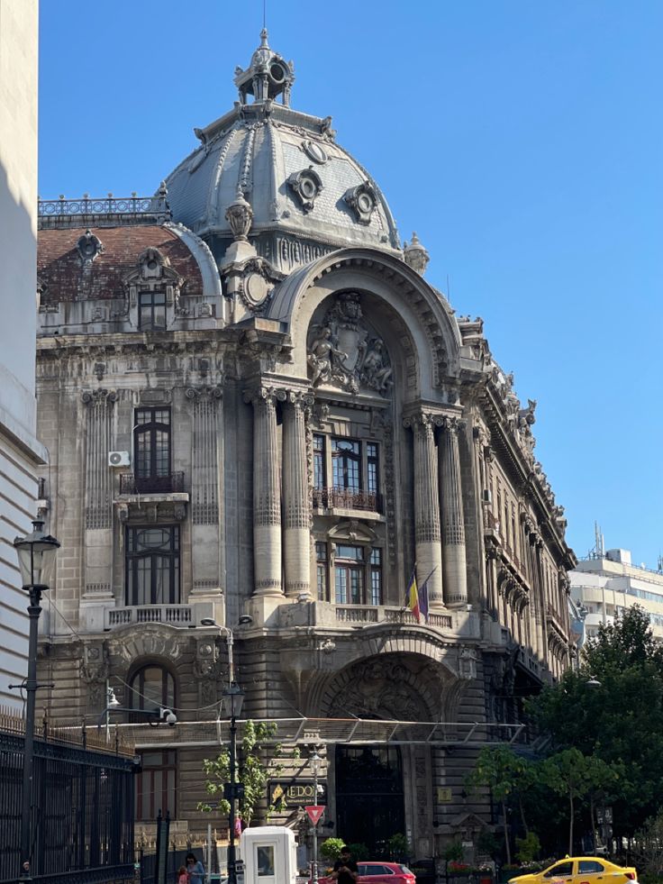 an old building in the middle of a city with cars parked on the street below it