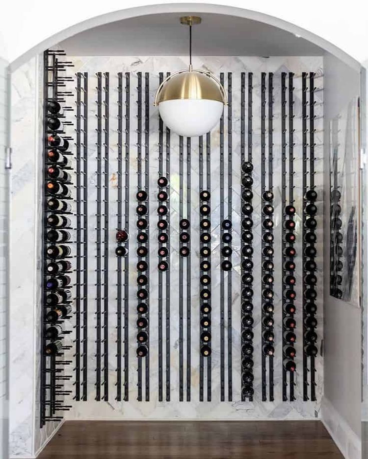 a wine rack in the corner of a room next to a wall with many bottles on it