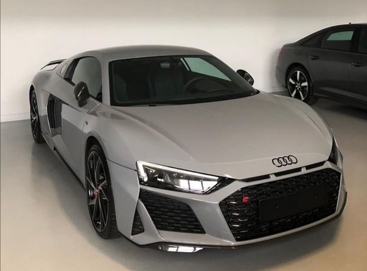 two cars are parked in a garage with one is grey and the other is black