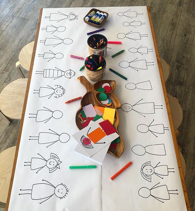 the table is covered with paper and crayons for children to draw on it