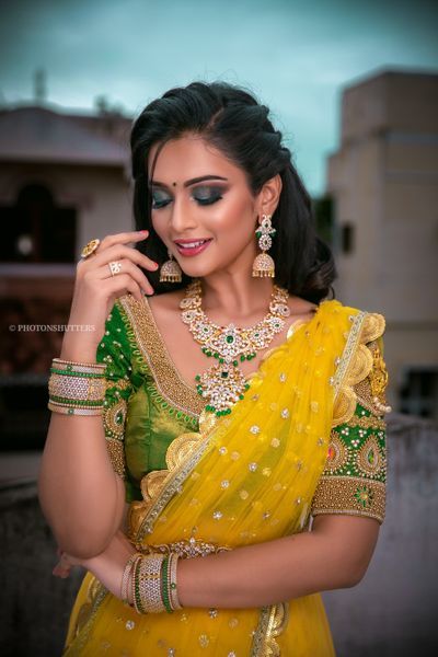 a beautiful woman in yellow and green sari posing for the camera with her hand on her cheek